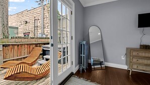A room with a wooden deck, a sliding glass door, a mirror, and a wooden dresser.