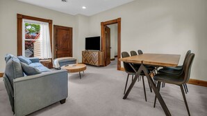 A spacious living room with a large sofa, a round coffee table, and a wooden dining table with chairs. - Lighthouse Loft– Chic Getaway in Marine City (Marine City)