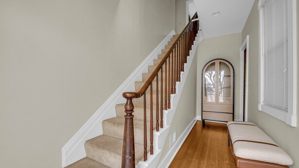 A staircase with wooden balusters and beige carpeted steps leading to a landing. - Lighthouse Loft– Chic Getaway in Marine City (Marine City)