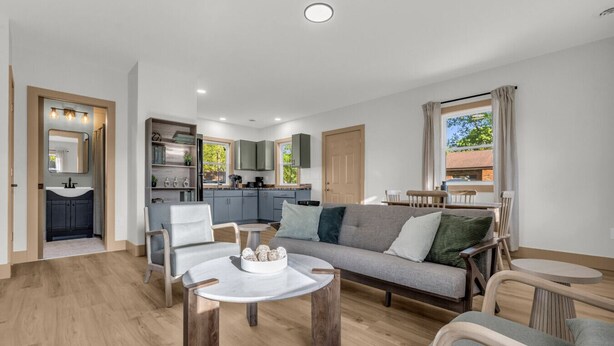 A modern living room with a sofa, chairs, a coffee table, and a kitchen in the background. - Oak & Clay Haven – Walk to Bar & Beach! (Fort Gratiot)