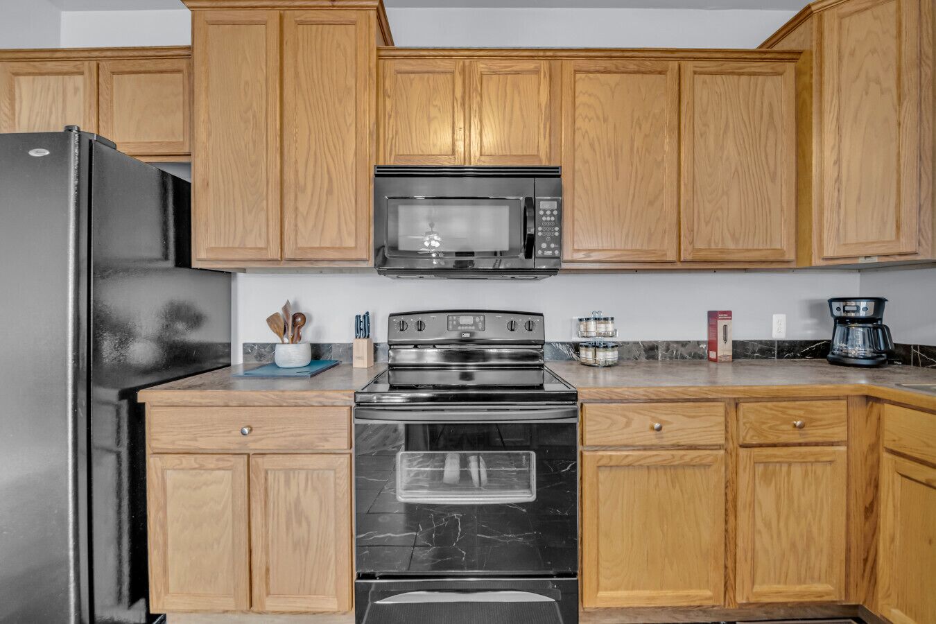 Een koelkast, kookgerei, borden en bestek, eettafels