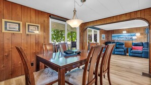A wooden-paneled room with a dining table, chairs, and a sofa. - Knot a Care - Lakefront Living with Great Views! (Port Hope)
