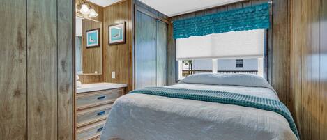 A bedroom with a bed, a dresser, a mirror, and framed pictures on the wall.