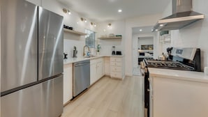 A modern kitchen with stainless steel appliances, white cabinetry, and a central island.