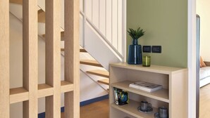 A staircase with a wooden railing, a bookshelf with decorative items, and a green wall with wall-mounted lights.