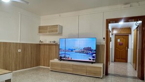 A room with a television on a wooden stand, a white wall, and a wooden door. - Your Mediterranean Home in Aguilas (Águilas)