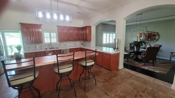 A spacious kitchen with a large island, wooden cabinets, and a dining area with a chandelier. - Serene Adult-Only Suite in the Heart of Houston (Houston)