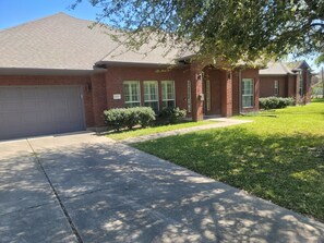 A residential house with a brick exterior, a garage, and a well-maintained lawn.