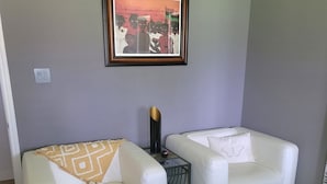 A living room with two white sofas, a framed artwork on the wall, and a dark wooden floor. - Serene Adult-Only Suite in the Heart of Houston (Houston)