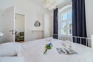 Un lit bien fait, avec des serviettes pliées, un magazine et un bouquet de fleurs.