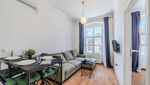 A modern living room with a dining table set for four, a sofa, and a small side table.