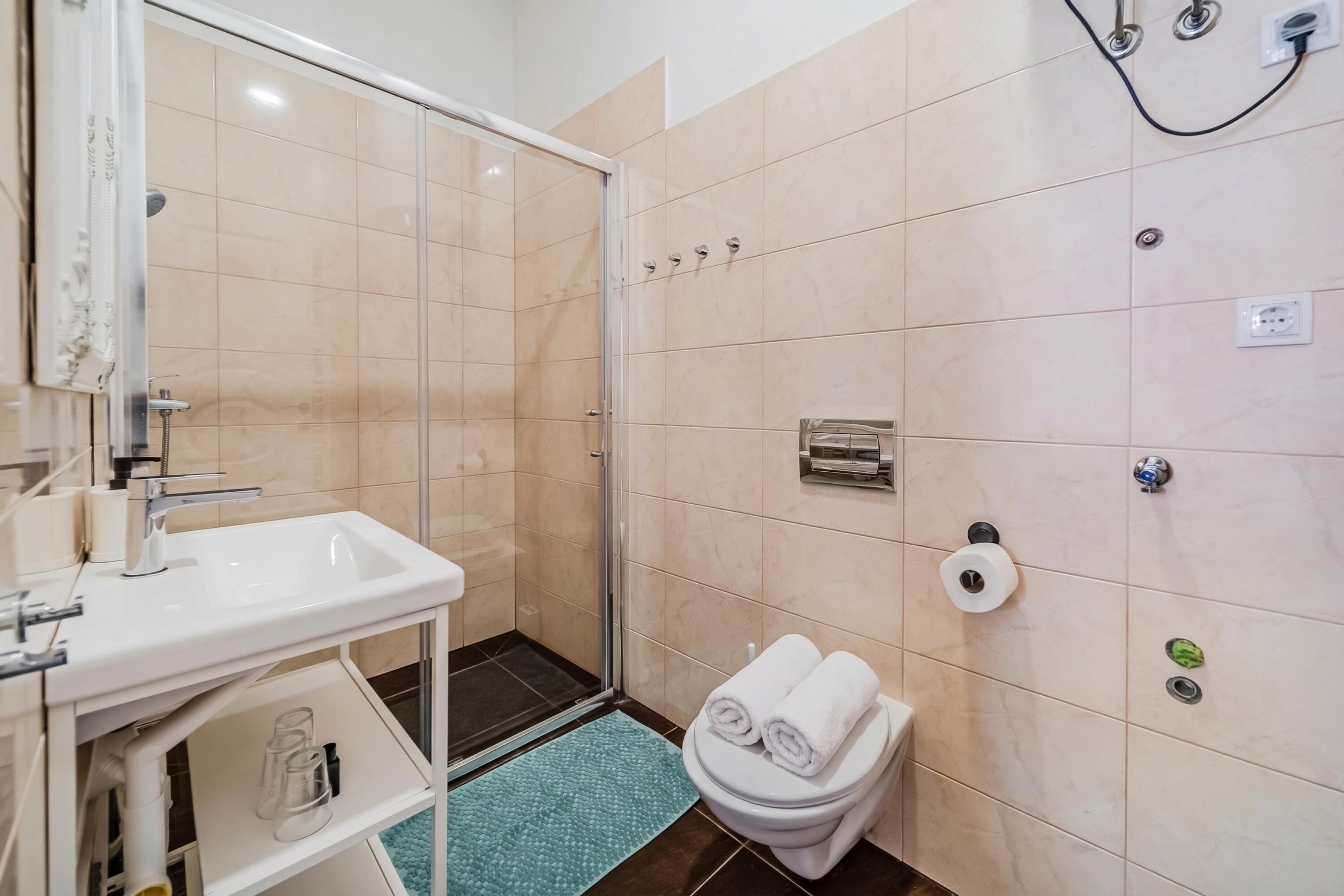 A bathroom with a shower, toilet, sink, and towel rack.