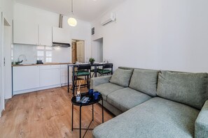 Un apartamento moderno con cocina, comedor y sala de estar, que incluye un sofá y una mesita.