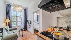 Een moderne keuken met een fornuis, een eethoek met een tafel en stoelen, en uitzicht op het omliggende landschap door grote ramen.