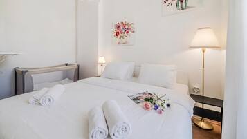 A hotel room with a neatly made bed, a bedside table with a lamp, and a wall-mounted artwork.