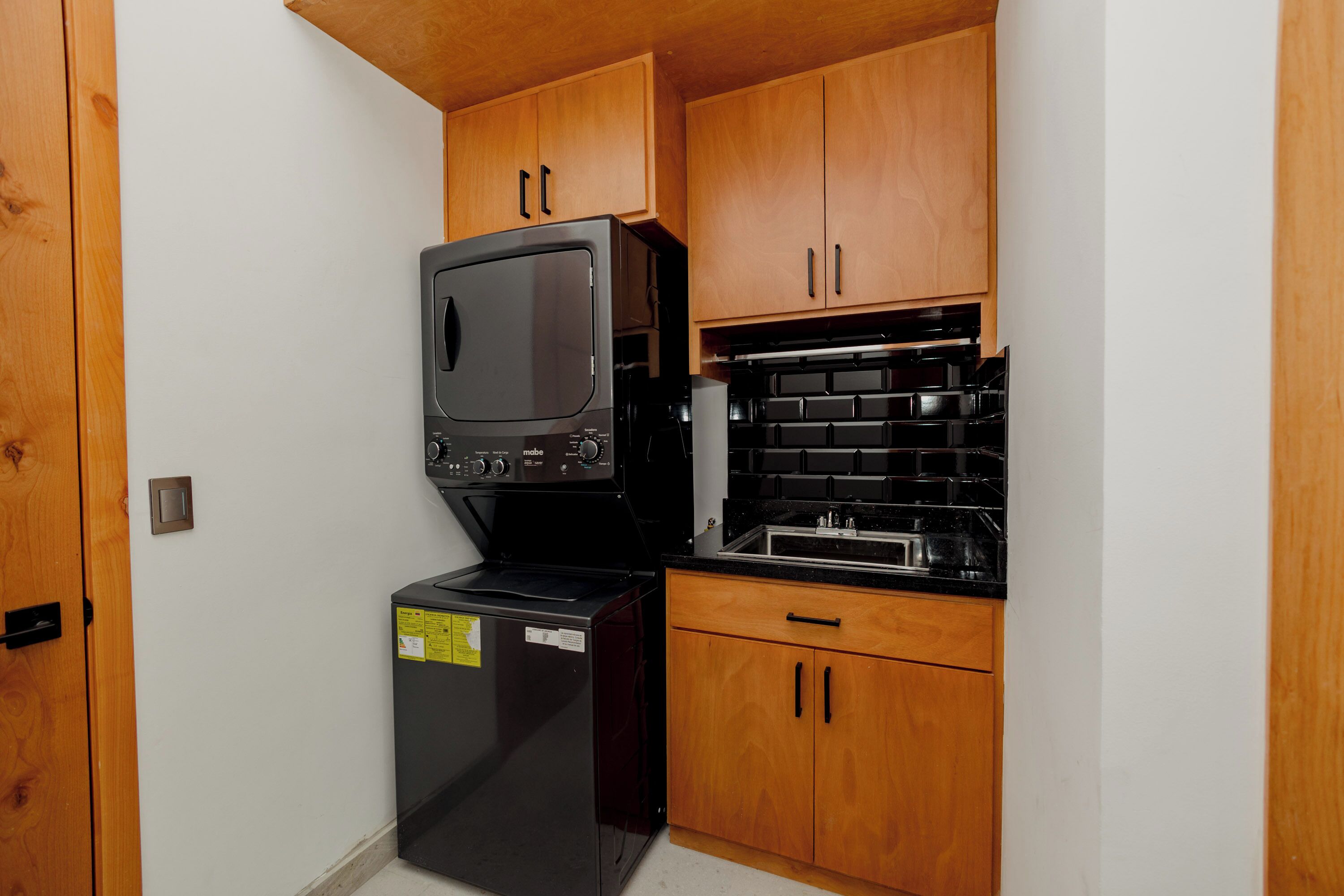 Eine kleine Küche mit Holzschränken, einem schwarzen Kühlschrank und einem Herd.