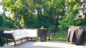 A covered patio with a white sofa, a planter, and a grill. - Opulent 4 Bdrm, Sleeps 12, Minutes From Downtown! (Cincinnati)