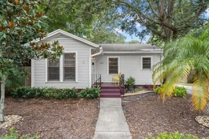 A single-story house with a front porch, a small garden, and a mailbox.