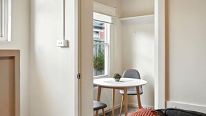 Una habitación compacta con una pequeña mesa redonda, dos sillas, una planta en maceta y un radiador.