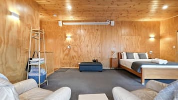 Ein Zimmer mit einem Bett, einem Schreibtisch, einem Sessel, einem kleinen Tisch und einem Regal mit Büchern.