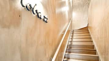 A wooden staircase with a handrail and a wall-mounted sign.