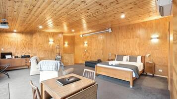 A room with a wooden ceiling, a bed, a desk, and a chair.