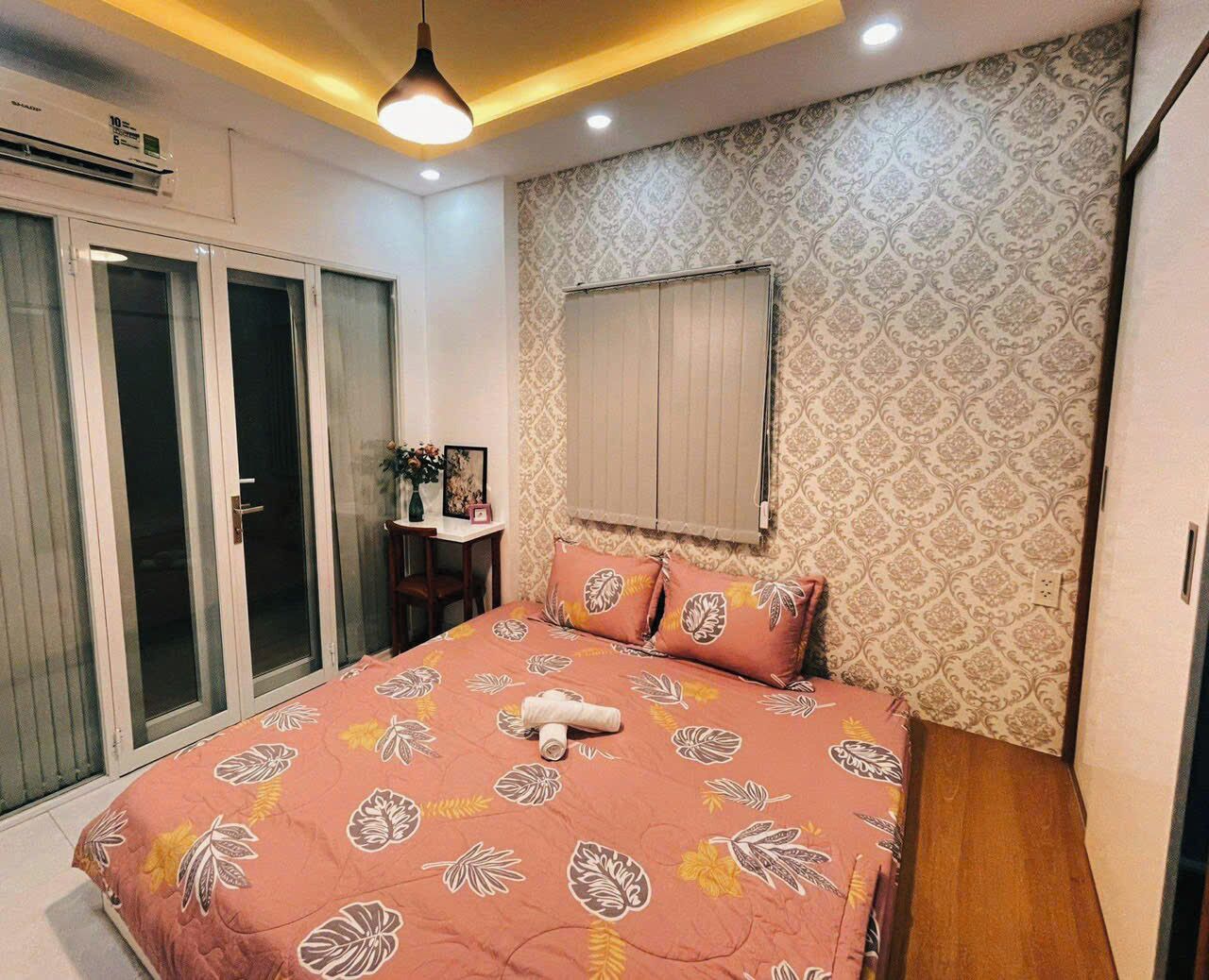 A bedroom with a bed, a desk, and a window with blinds.