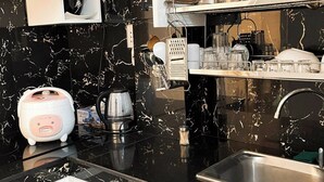 Una cocina moderna con encimeras de mármol negro, electrodomésticos de acero inoxidable y horno empotrado.