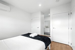 Camera da letto moderna con un letto, una coperta nera e un condizionatore d'aria bianco a parete.
