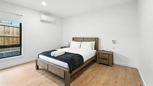 A modern bedroom with a wooden bed, white bedding, and a nightstand. - Modern & Accessible | Old Beach (Old Beach)
