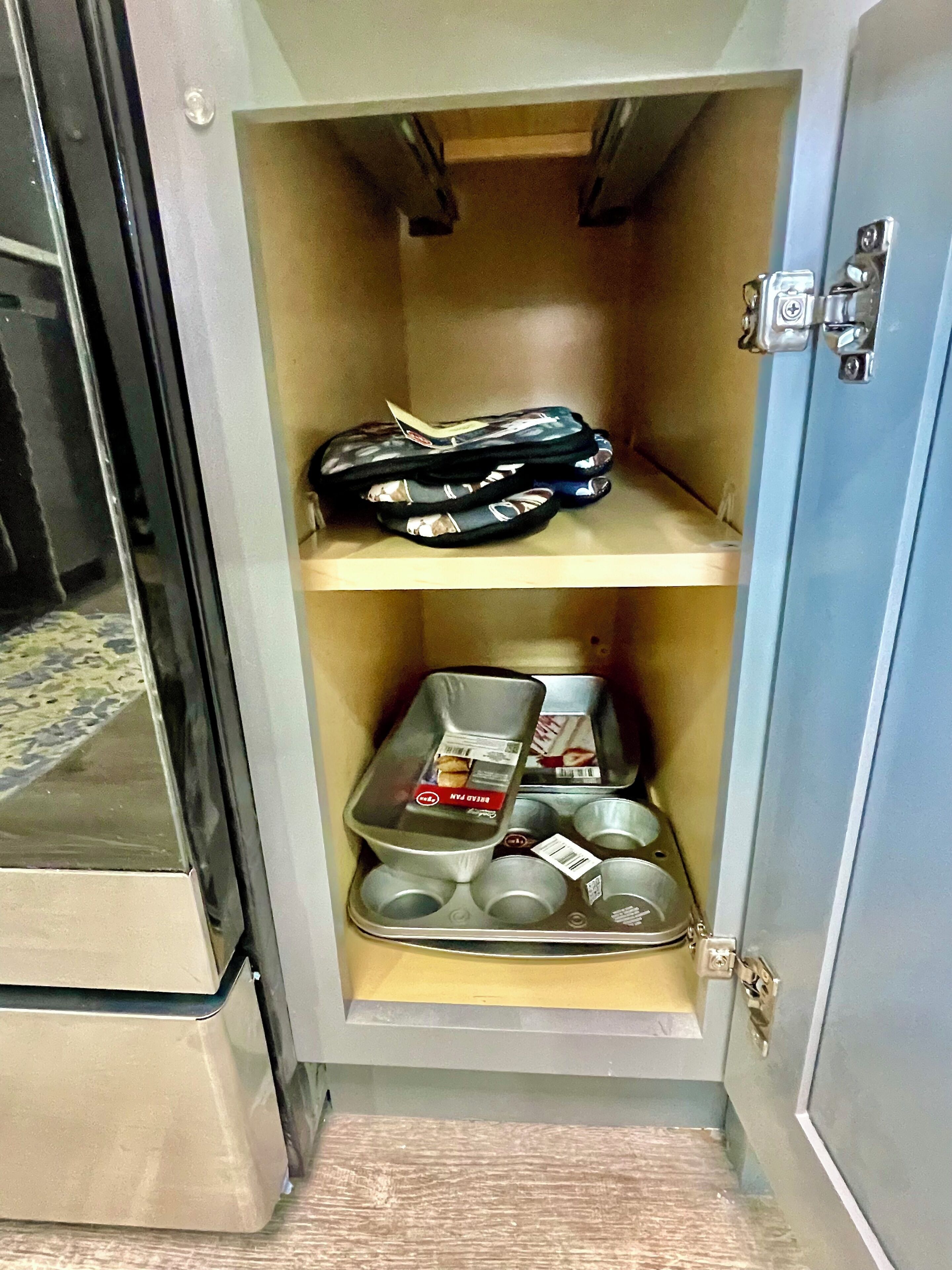 Un armari amb dos prestatges, un ple de tovalloles plegades i l'altre amb una safata que conté diverses tasses i una caixa amb la inscripció "Belly Pan".