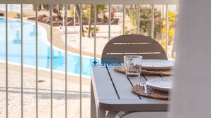 Et bord ved poolen med et glas og tallerkener, med udsigt til swimmingpoolen.