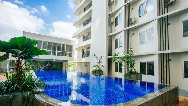 A modern building with a swimming pool surrounded by potted plants. - Padina Soho and Residence (Tangerang)
