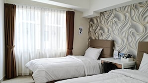 A hotel room with two beds, a bedside table with a lamp, a wall-mounted artwork, and a window with curtains. - Padina Soho and Residence (Tangerang)