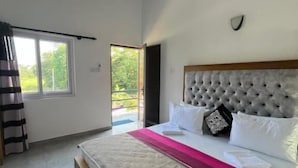 Un dormitorio con una cama grande, un ventilador de techo, una ventana y una puerta que da a un espacio exterior.