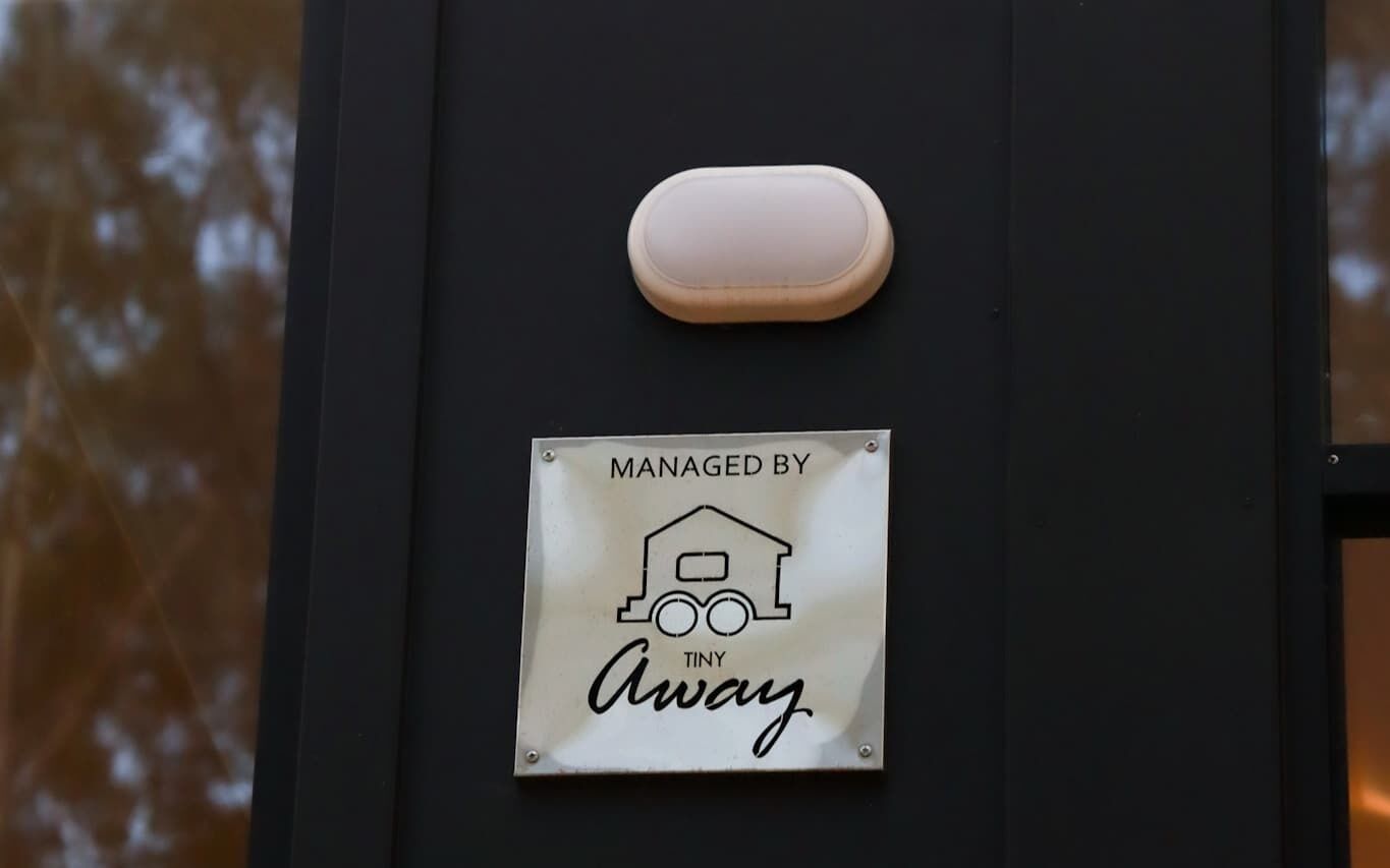 Eine Tür mit einem Schild, das „MANAGED BY TINY Away“ zeigt, und einem kleinen, ovalen Gegenstand darüber.