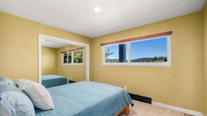 Une chambre à coucher avec un lit, une fenêtre donnant sur un beau paysage et un miroir.