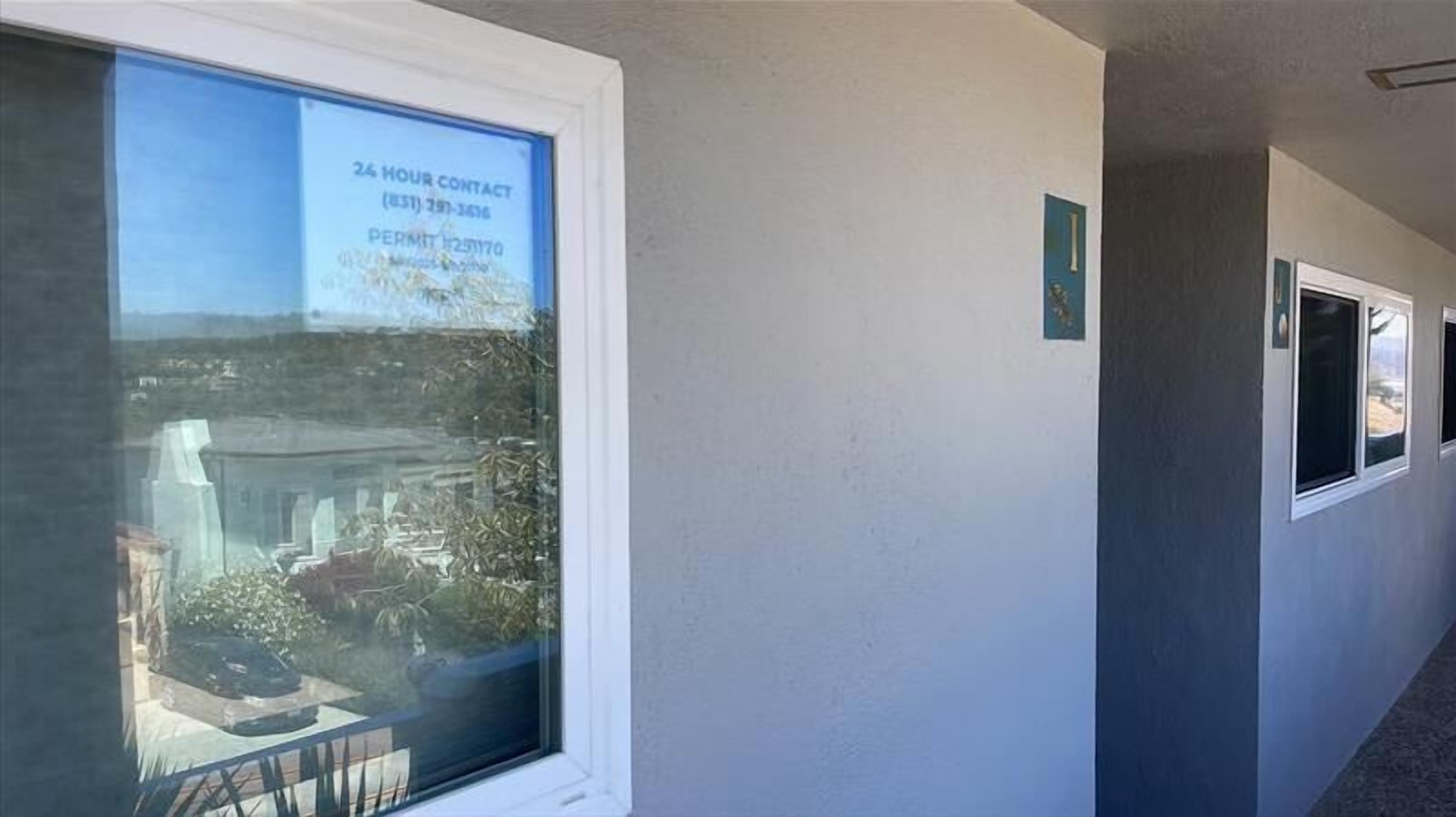 Ein Korridor mit einem großen Fenster, das eine 24-Stunden-Kontaktnummer und eine Genehmigungsnummer zeigt.