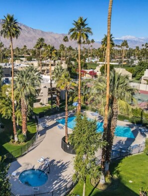 Un resort con diverse piscine, palme e montagne sullo sfondo.