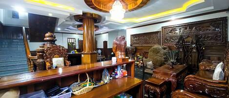 A room with a wooden bar area, shelves with various items, and a decorative ceiling.