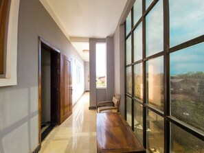 A hallway with a wooden bench, large windows, and a door leading to another room. - Sat Chamroeun Residence  (Siem Reap)