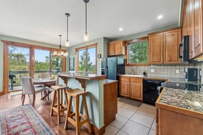 A kitchen with wooden cabinets, a large island, and a dining area with a view. - Snowflake Lift Access | Hot Tub + Views (Breckenridge)