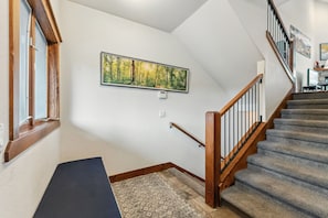 A staircase with wooden railings and carpeted steps leading to a landing.