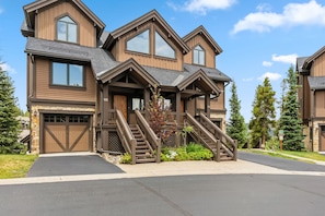 A multi-story house with a stone foundation, a garage, and a staircase leading to the upper floor.