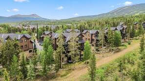 A resort with multiple wooden buildings surrounded by dense forest and mountains in the background. - Snowflake Lift Access | Hot Tub + Views (Breckenridge)