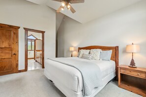 A bedroom with a large bed, wooden headboard, two bedside lamps, and a wooden nightstand.