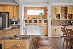 Una cucina moderna con mobili in legno, un piano di lavoro in granito e un'isola centrale con sgabelli.