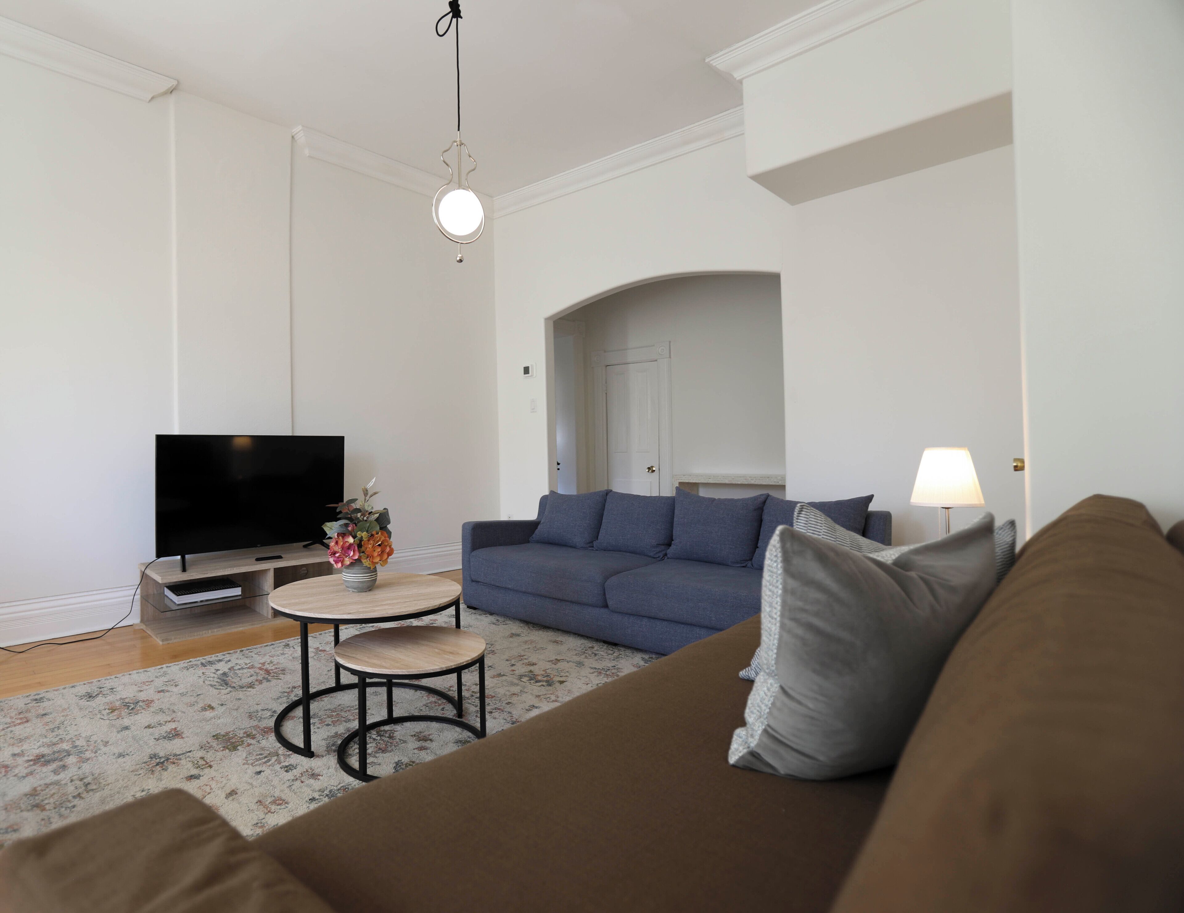 A living room with a flat-screen TV, a sofa, a coffee table, and a lamp.
