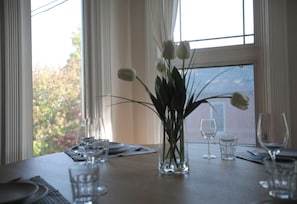 A dining table set with plates, cutlery, and wine glasses, with a vase of flowers in the center.