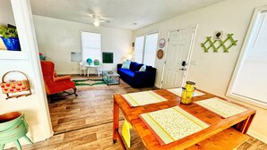 A living room with a wooden table, a red armchair, and a blue sofa. - Cozy, Country Cottage (Travelers Rest)